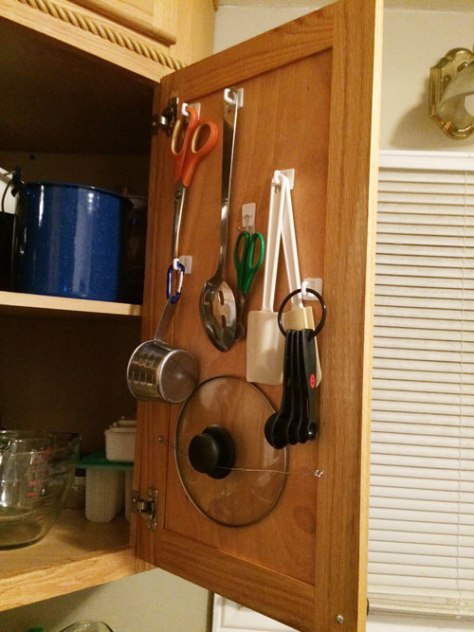 Stick-on hooks aren't exactly a new concept, but I reclaimed some unused space by putting them inside a cabinet door above my jury-rigged pot-lid holder.